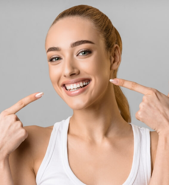 Woman with porcelain veneers pointing to smile