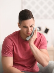 Man holding jaw in pain before TMJ therapy